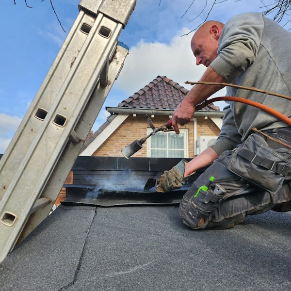 Freddy Sallomons aan het werk met bitumen dakbedekking.